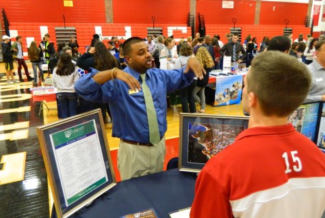 Jameel Moore, assistant director of admission at Endicott College, talks with a prospective applicant at the annual College Fair at Watertown High School on Oct. 9, 2014. 