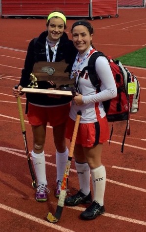 Watertown High cocaptains Allie Doggett (left) and Emily Loprete pose with the Division 2 trophy after the Raider defeated Auburn, 5-0, on Sunday, Nov. 16, 2014, for the state title. Doggett, Loprete, and their senior classmates completed their WHS field hockey careers without ever suffering a loss.