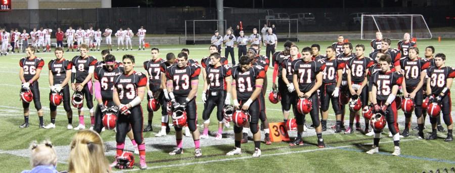 The Watertown High football stands at attention during the playing of the national anthem before the Raiders Senior Night game at Victory Field with Melrose on Oct. 10, 2014.