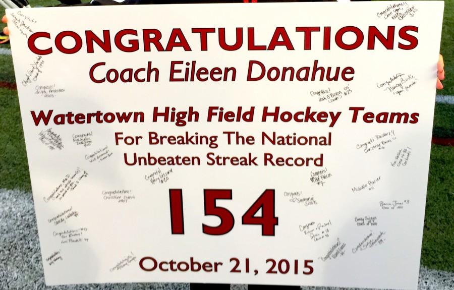 Members of the Watertown High School field hockey team autographed a congratulations sign celebrating the Raiders’ record-setting 154th game without a loss Oct. 21, 2015. 