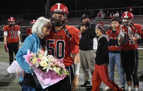 Max Bunnell (50) presents flowers to Donna Maher before the Raiders game with Wakefield at Victory Field on Oct. 19, 2018.  Watertown Highs Think Pink Week was dedicated this year to Maher, a three-time cancer survivor.