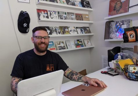 Joey Cahill, owner of Wanna Hear It Records, sits at the counter of his Watertown Square store.
